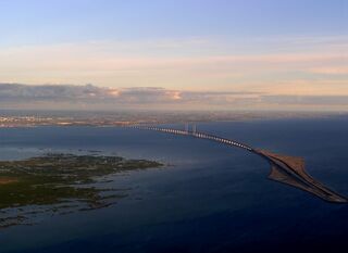 Öresund Bridge from Denmark to Sweden. On the right the artifical island Peberholm and on the left Saltholm. The islands shown belong to Denmark. The Swedish city of Malmö is seen on the horizon.