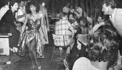 Transwoman sashaying down Bugis Street, being ogled at by tourists, circa the 1960s