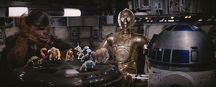 Chewbacca pelaa dejarikia R2-D2:ta vastaan Millenium Falconilla. C-3PO seuraa peliä.