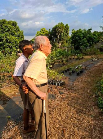 Mr. Pojana Nagavajara in his Rose garden, looking after the rose named for him.